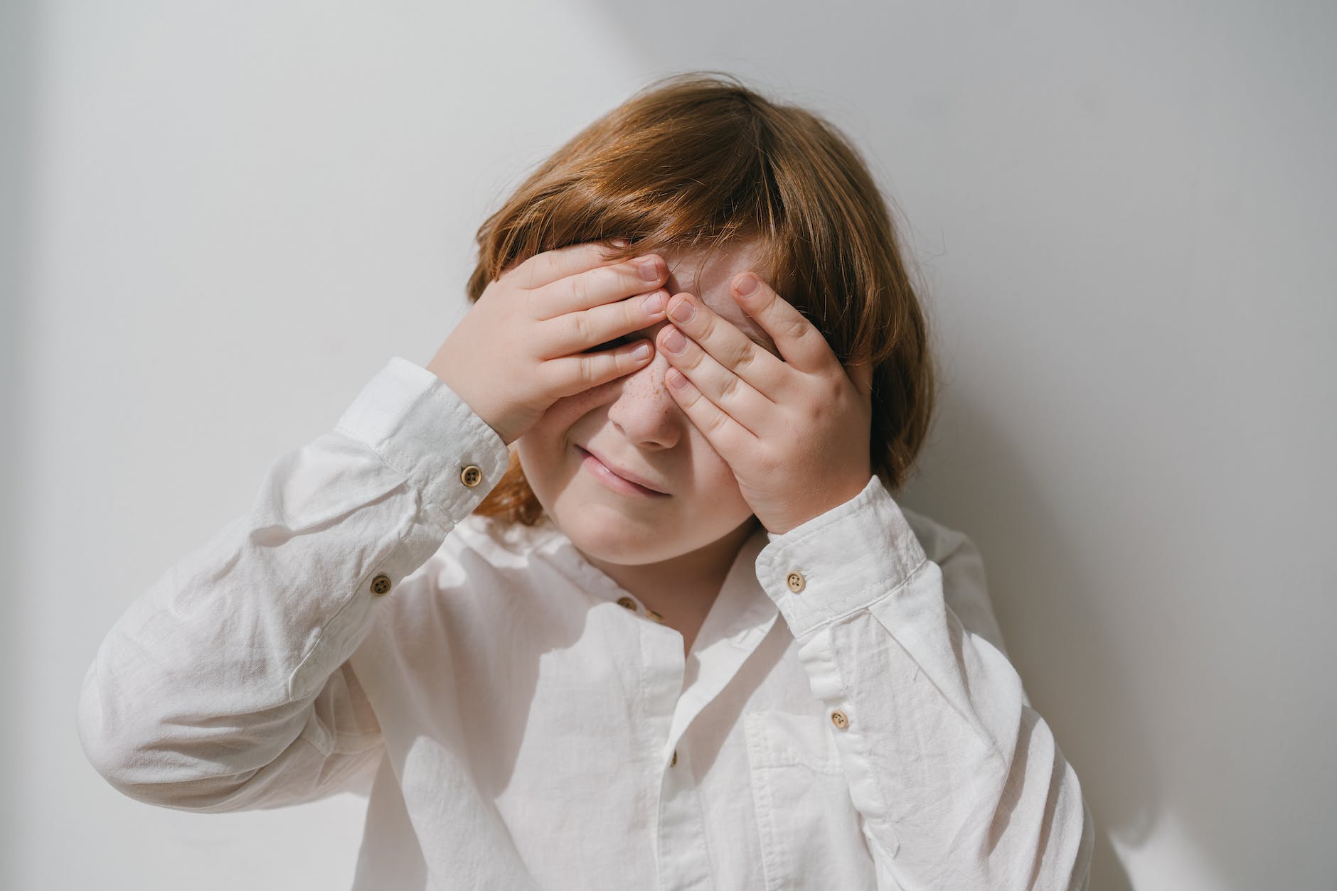 photograph of a boy covering his eyes