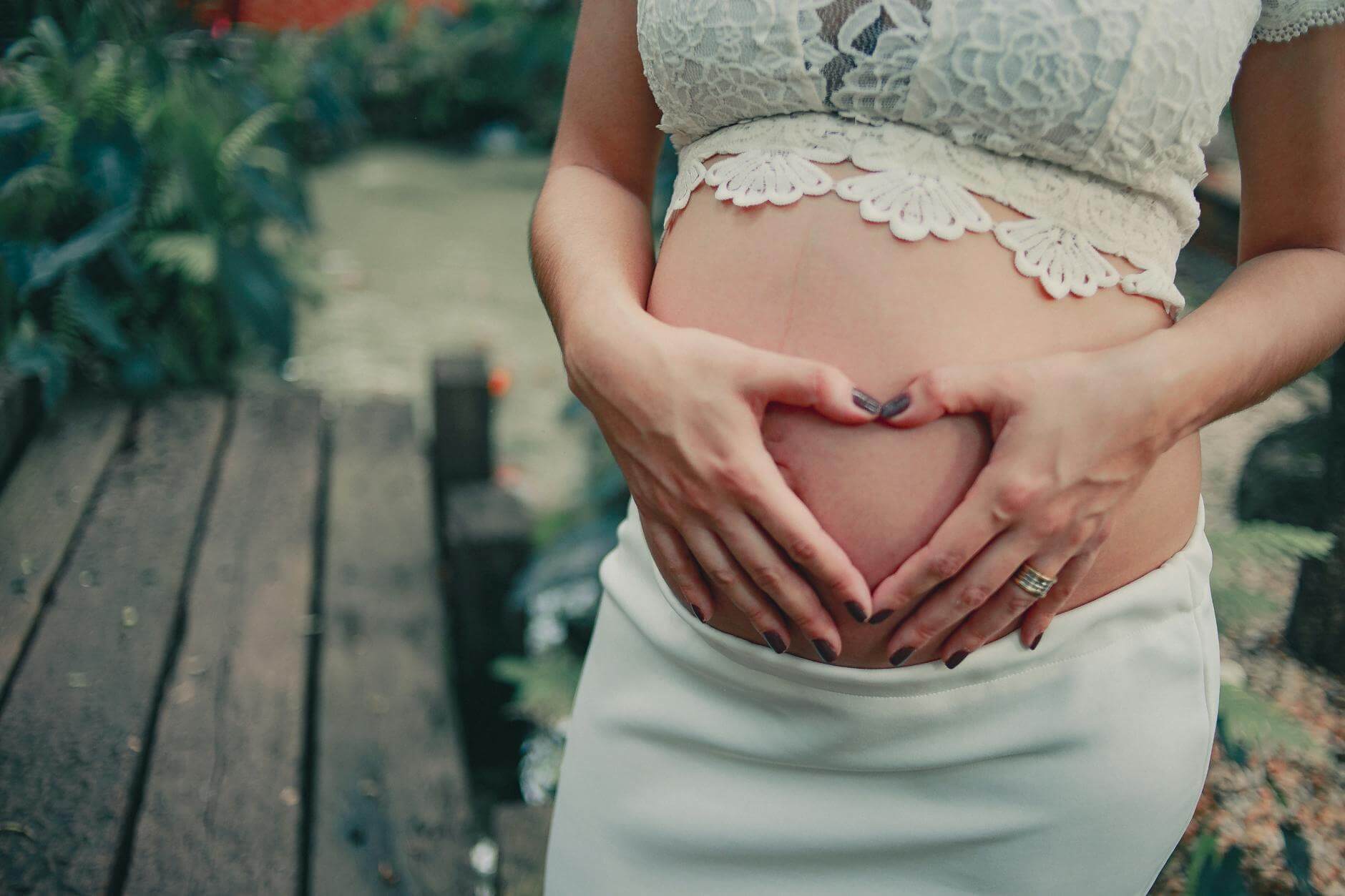 pregnant woman wearing white skirt holding her tummy