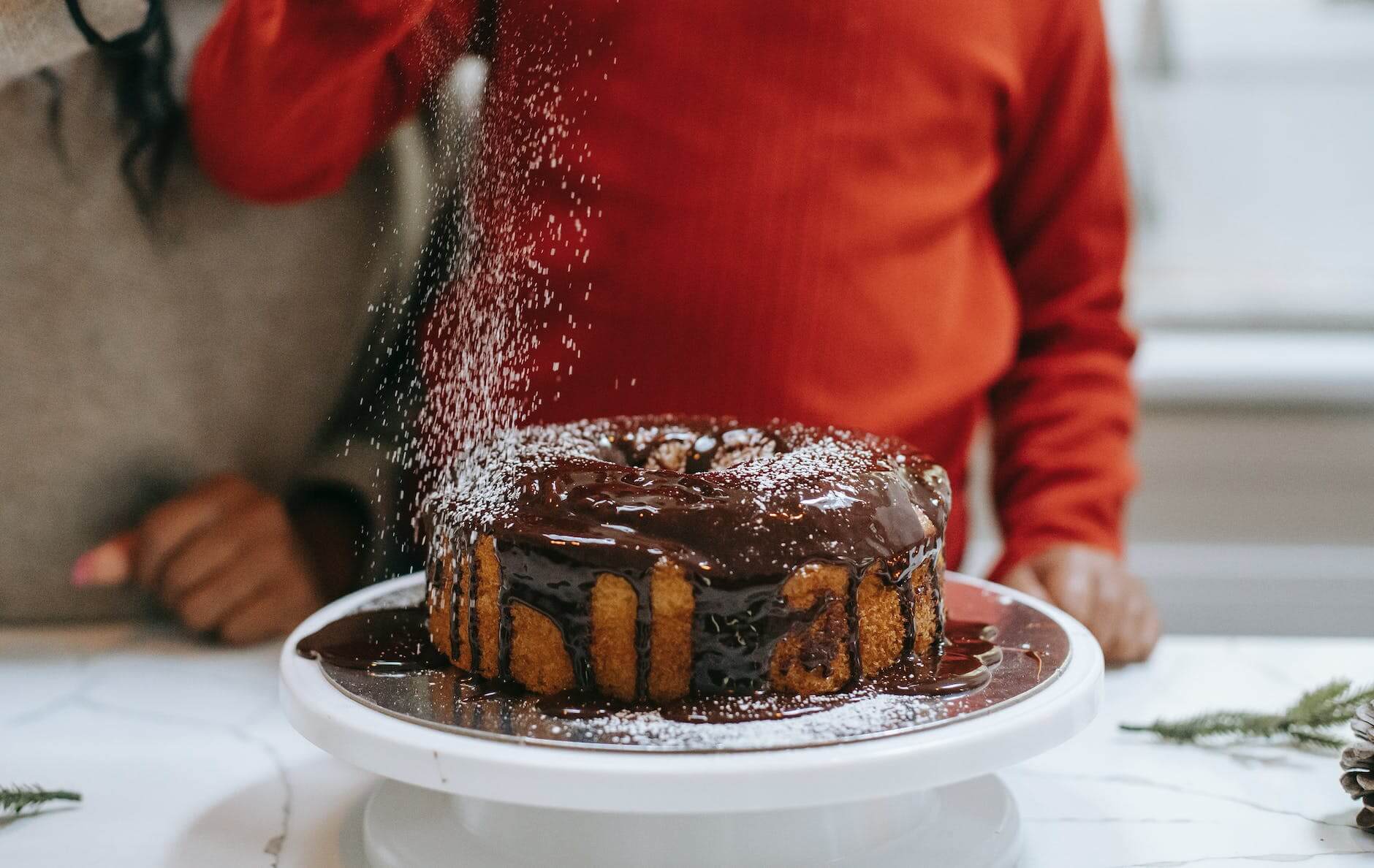 crop black mother with kid decorating cake with powdered sugar