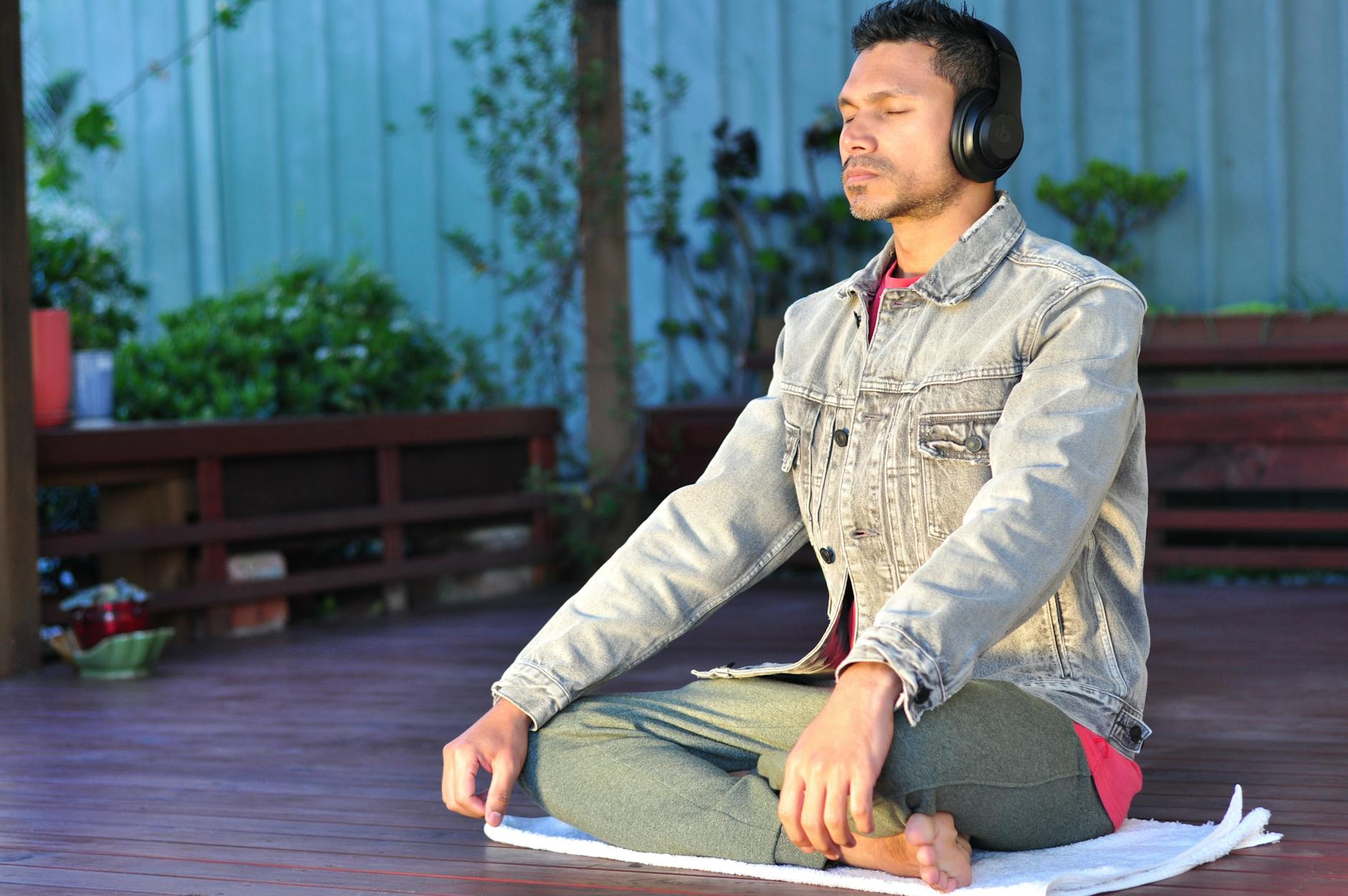 a man in denim jacket listening to music while meditating with his eyes closed