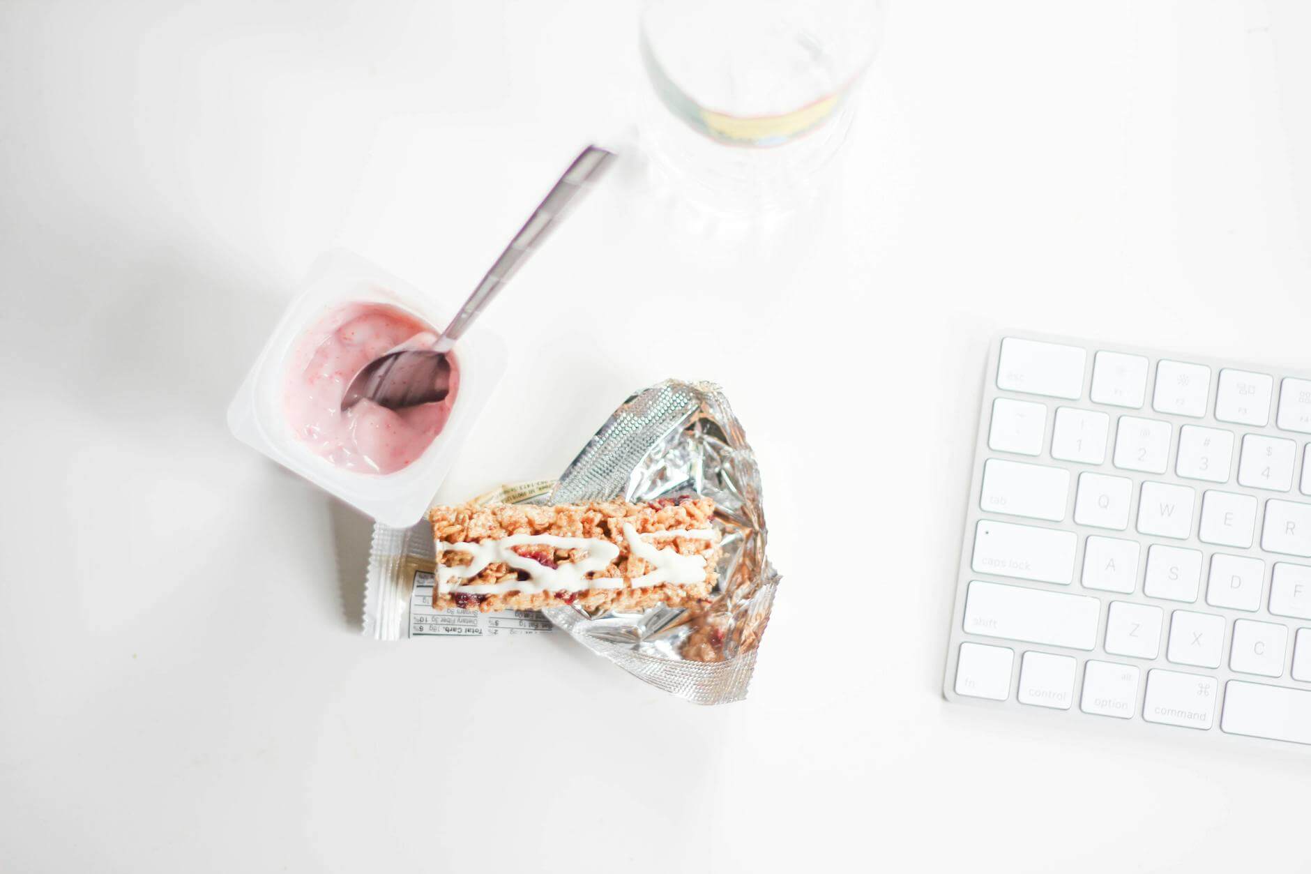 flat lay photography of yogurt with pack of crackers and apple magic keyboard