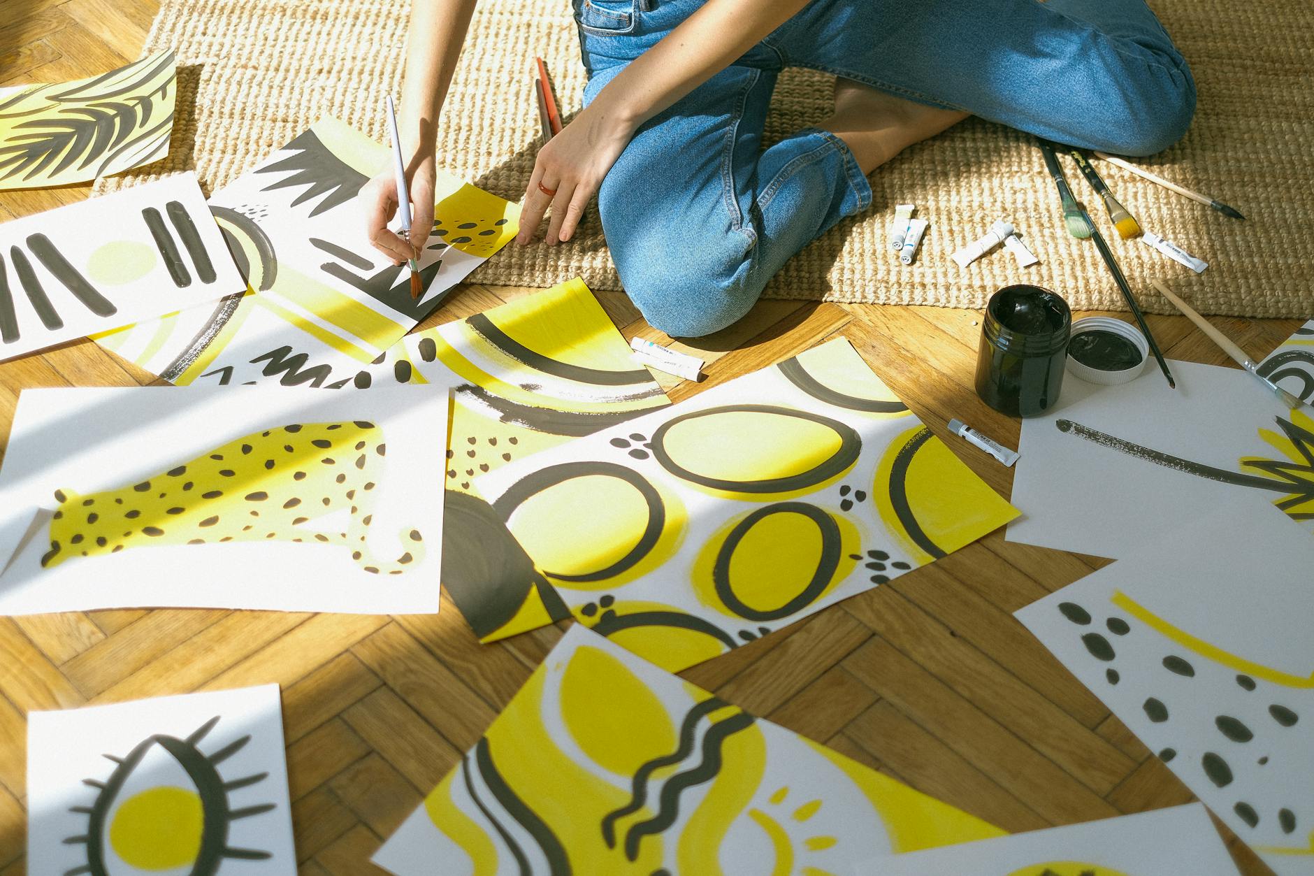 person in blue denim jeans sitting while painting