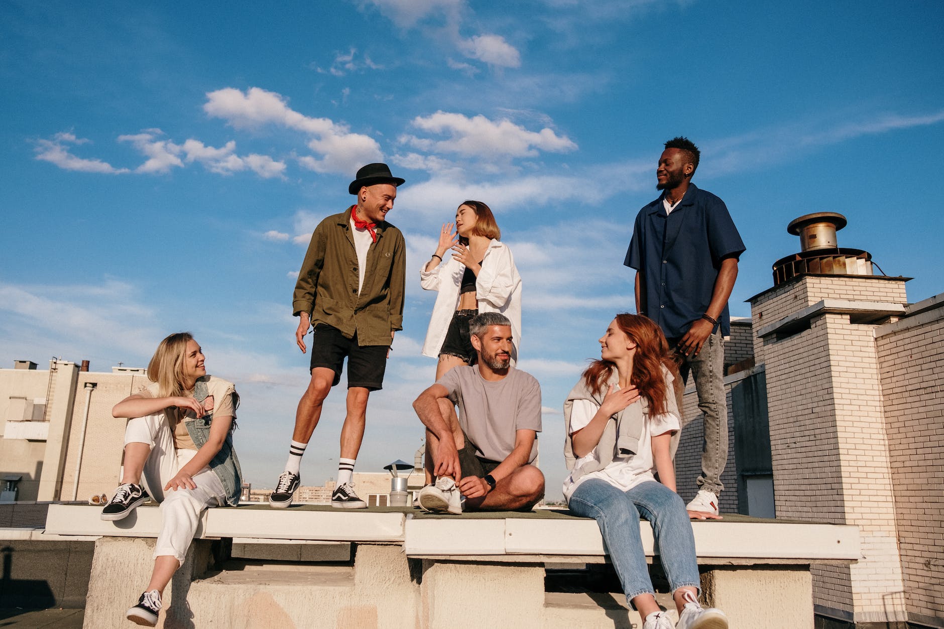 a group of multi-racial friends hanging out together happily on a roof top