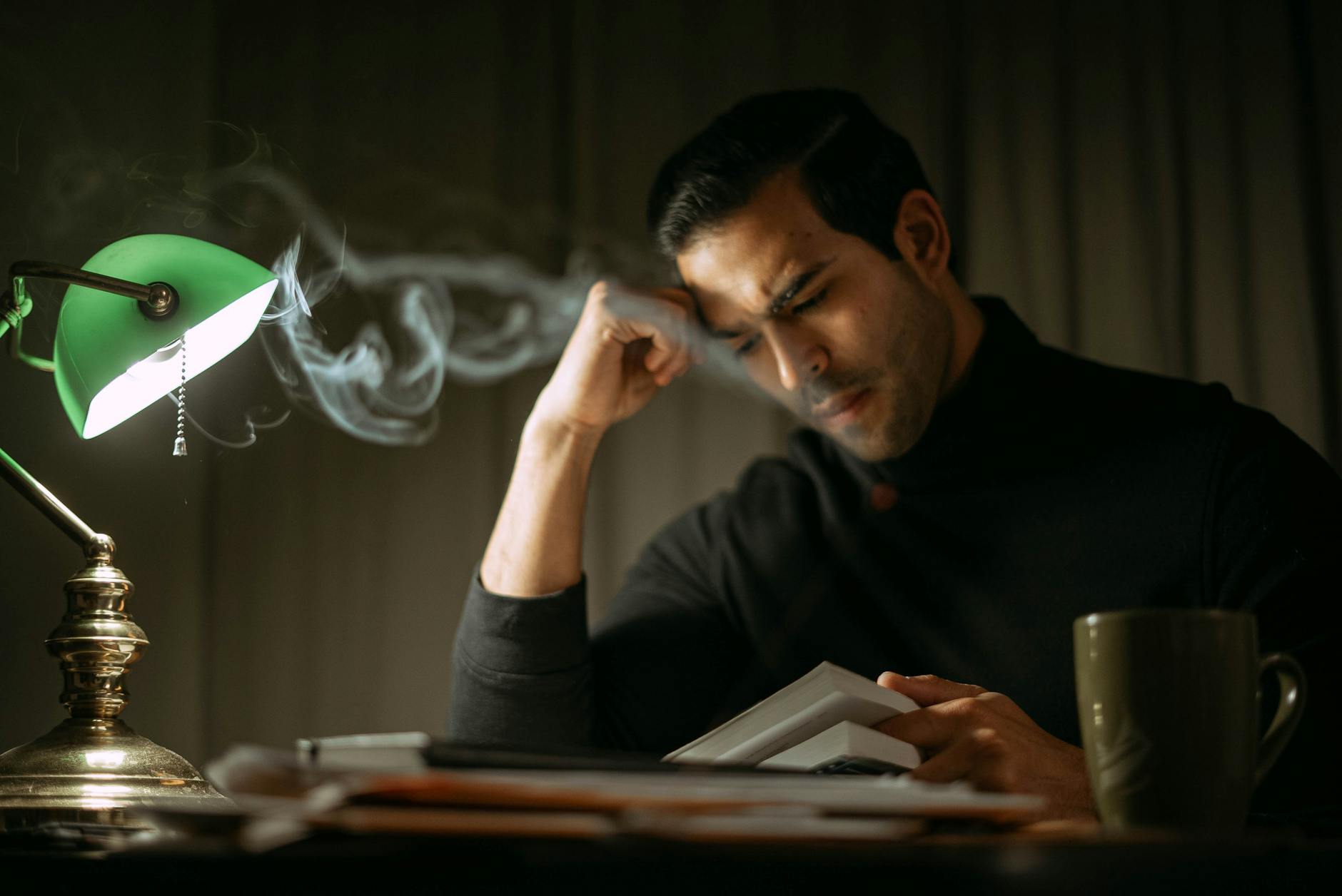 focused man reading book in lamplight